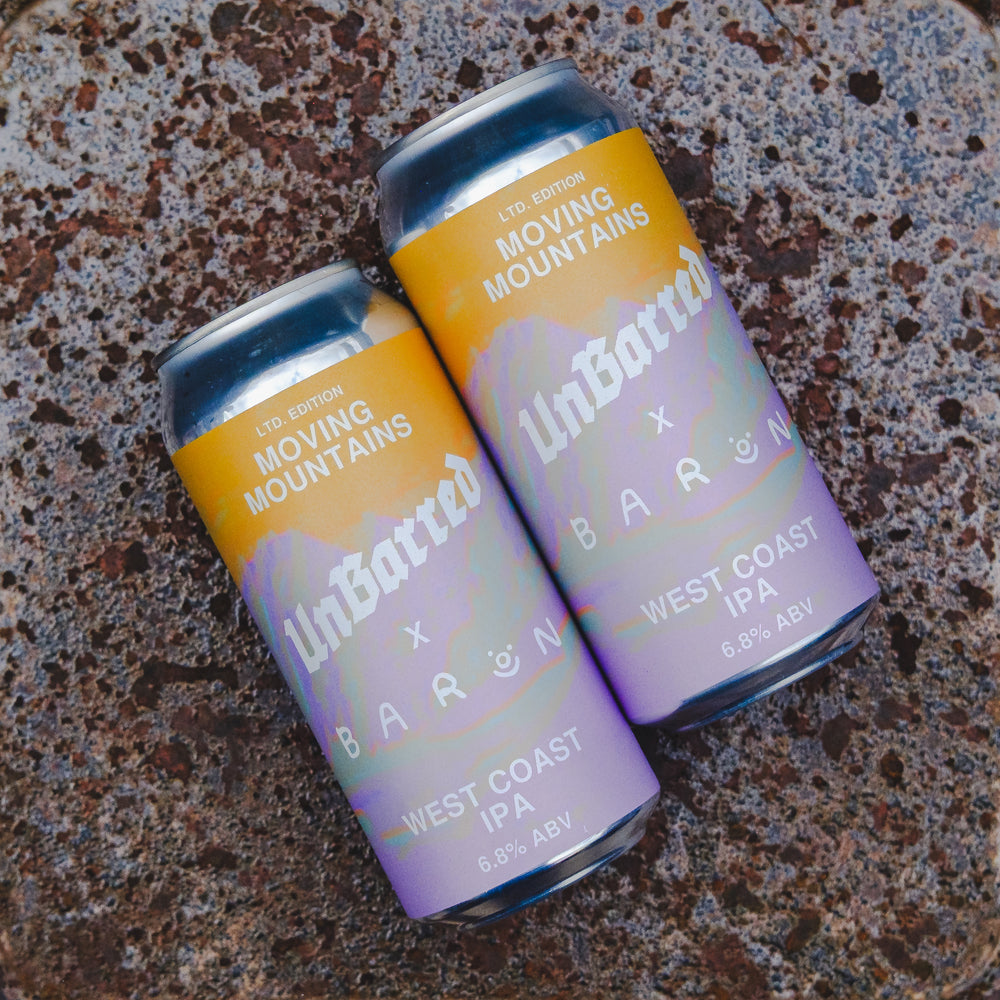Two aluminum craft beer cans labeled 'UnBatted x BARON Moving Mountains West Coast IPA' resting on a textured speckled surface.